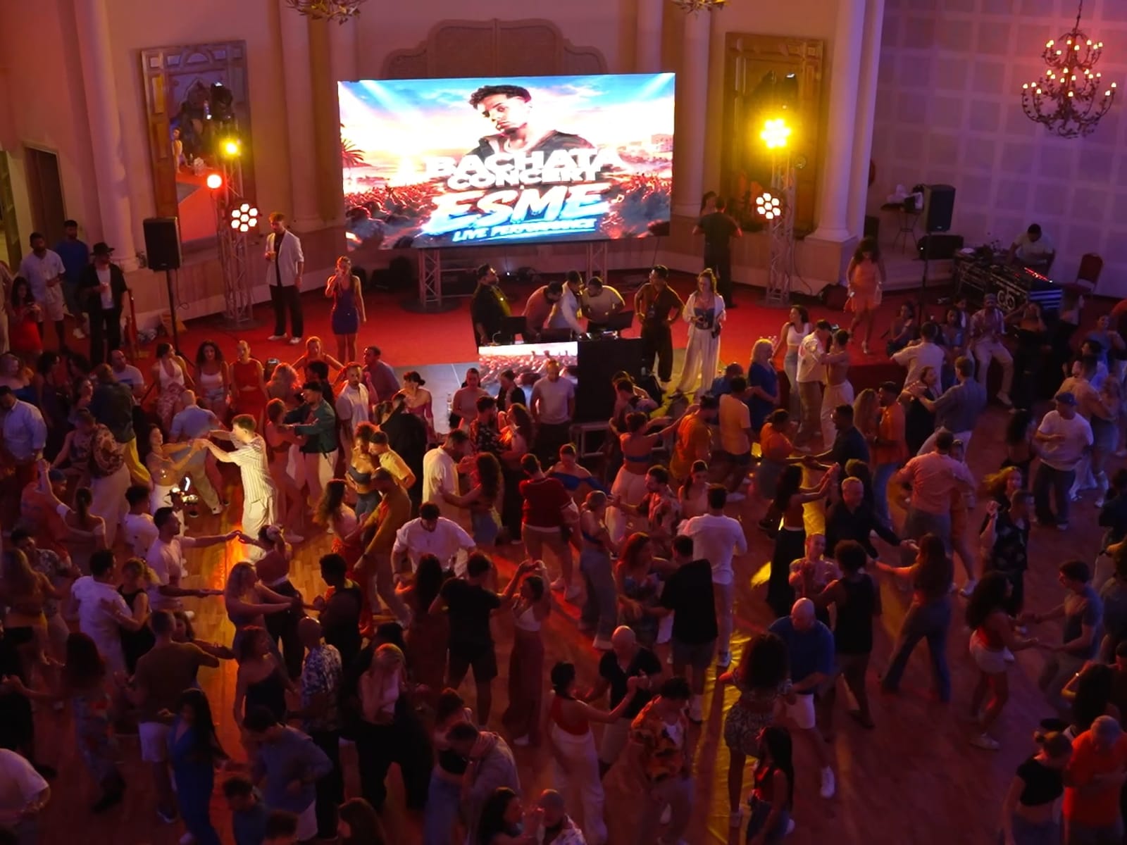 The crowd dancing under chandeliers at a live concert